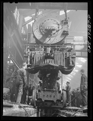 Untitled photo, possibly related to: Topeka, Kansas. Wheeling an engine of the 3200 freight class in the Atchison, Topeka and Santa Fe Railroad locomotive shops. The engine is about to be lowered onto its wheels
