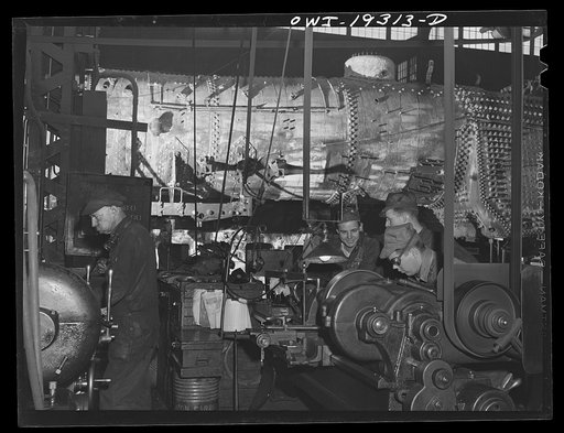 Topeka, Kansas. Working on the fire box end of an engine in the Atchison, Topeka and Santa Fe Railroad locomotive shop. In the background is an engine stripped for overhauling
