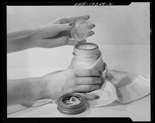 Steel-saving glass-top jars recommended by the War Production Board, Containers Division, for home canning of the Victory garden fruits and vegetables in 1943. First step in sealing a jar is to fit the wet, sterilized rubber ring around the projection on the underside of the glass lid, also steriliz