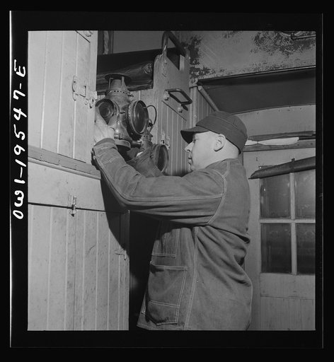 As darkness approaches, brakeman M. H. Burdette lights his markers and gets them ready to hang on the rear end of the caboose on the Atchison, Topeka and Santa Fe Railroad between Chillicothe, Illinois and Fort Madison, Iowa