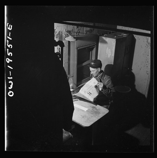 A conductor studying a timetable in the caboose on the Atchison, Topeka and Santa Fe Railroad between Chillicothe, Illinois and Fort Madison, Iowa