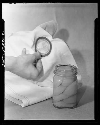 Steel-saving glass-top jars recommended by the War Production Board, Containers Division, for home canning of the Victory garden fruits and vegetables in 1943. First step in sealing a jar is to fit the wet, sterilized rubber ring around the projection on the underside of the glass lid, also steriliz