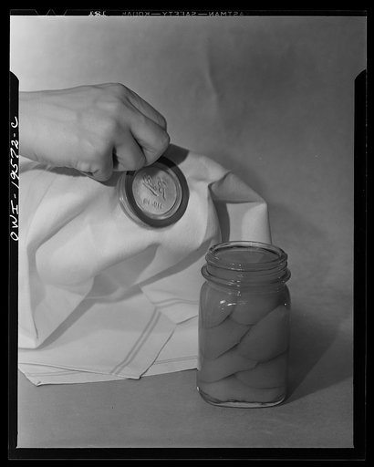 Steel-saving glass-top jars recommended by the War Production Board, Containers Division, for home canning of the Victory garden fruits and vegetables in 1943. First step in sealing a jar is to fit the wet, sterilized rubber ring around the projection on the underside of the glass lid, also steriliz