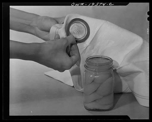 Steel-saving glass-top jars recommended by the War Production Board, Containers Division, for home canning of the Victory garden fruits and vegetables in 1943. First step in sealing a jar is to fit the wet, sterilized rubber ring around the projection on the underside of the glass lid, also steriliz