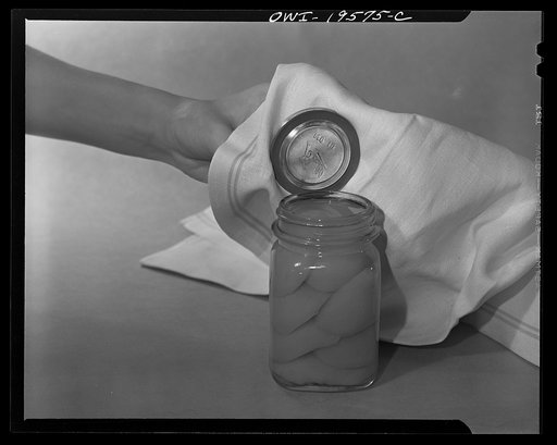 Steel-saving glass-top jars recommended by the War Production Board, Containers Division, for home canning of the Victory garden fruits and vegetables in 1943. First step in sealing a jar is to fit the wet, sterilized rubber ring around the projection on the underside of the glass lid, also steriliz