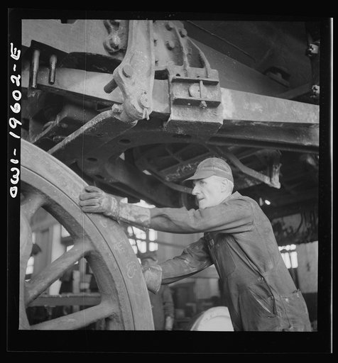 Fort Madison, Iowa. Edward E. Leonard pushing a driver wheel in place under an engine being wheeled at the Shopton locomotive shops of the Atchison, Topeka, and Santa Fe Railroad