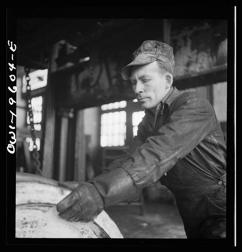 Fort Madison, Iowa. W. Phillips pushing a truck wheel in place under an engine being wheeled at the Shopton locomotive shops of the Atchison, Topeka, and Santa Fe Railroad