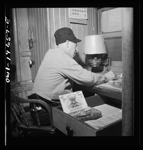 Conductor F. T. Granstaff, working on his records in the caboose on the Atchison, Topeka, and Santa Fe Railroad between Marceline, Missouri and Argentine, Kansas
