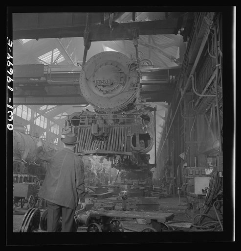 Topeka, Kansas. Lifting an engine with the eighty-ton cranes at the Atchison, Topeka, and Santa Fe Railroad locomotive shops. This locomotive will be carried to another part of the shop to be wheeled