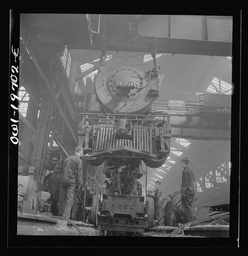 Untitled photo, possibly related to: Topeka, Kansas. Lifting an engine with the eighty-ton cranes at the Atchison, Topeka, and Santa Fe Railroad locomotive shops. This locomotive will be carried to another part of the shop to be wheeled