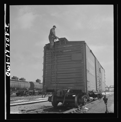Argentine, Kansas. A switchman riding a car in the Atchison, Topeka, and Santa Fe Railroad yard
