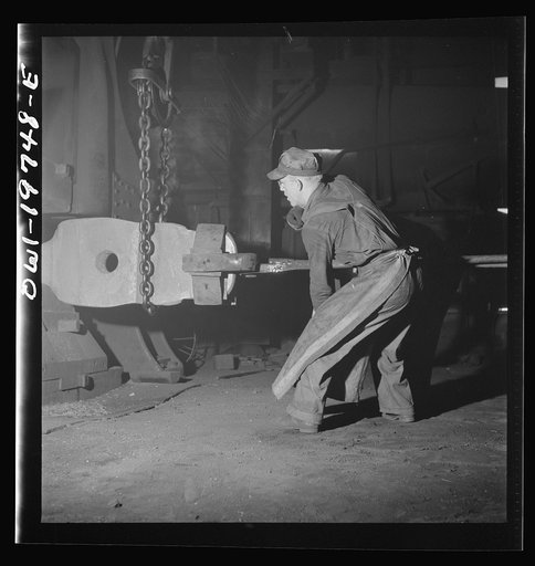 Topeka, Kansas. Workmen manipulating a hot forging which is being hammered under a steam hammer in the blacksmith shop of the Atchison, Topeka and Santa Fe Railroad