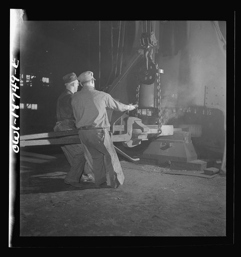 Topeka, Kansas. Workmen manipulating a hot forging which is being hammered under a steam hammer in the blacksmith shop of the Atchison, Topeka and Santa Fe Railroad