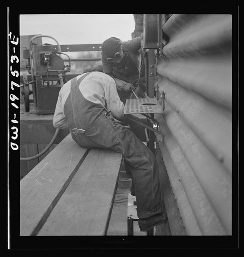 Untitled photo, possibly related to: Topeka, Kansas. Bucking rivets on a freight car which is being rebuilt in the shops of the Atchison, Topeka and Santa Fe Railroad