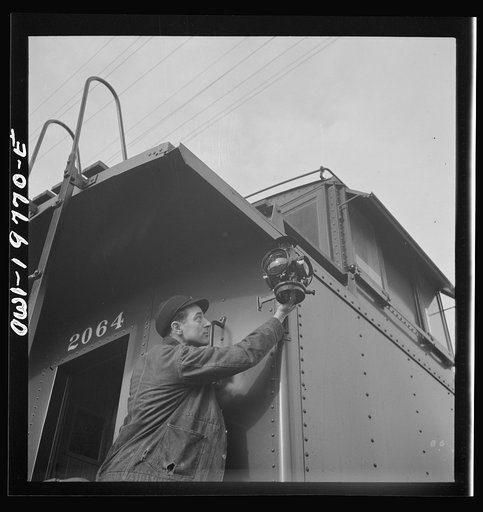 Argentine, Kansas. Brakeman Kenneth N. Dean hanging markers on the caboose as his Atchison, Topeka and Santa Fe train gets ready to leave, between Argentine and Emporia, Kansas