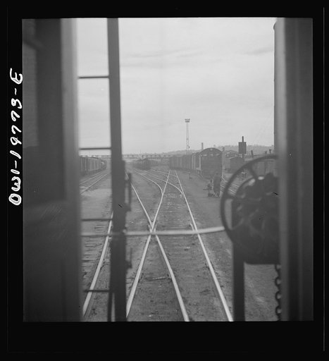 Untitled photo, possibly related to: Argentine, Kansas. Atchison, Topeka, and Santa Fe Railroad train pulling out of the railroad yard, past the giant grain elevator