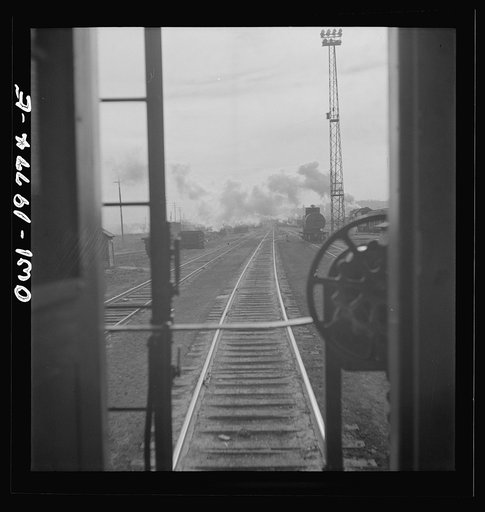 Untitled photo, possibly related to: Argentine, Kansas. Atchison, Topeka, and Santa Fe Railroad train pulling out of the railroad yard, past the giant grain elevator