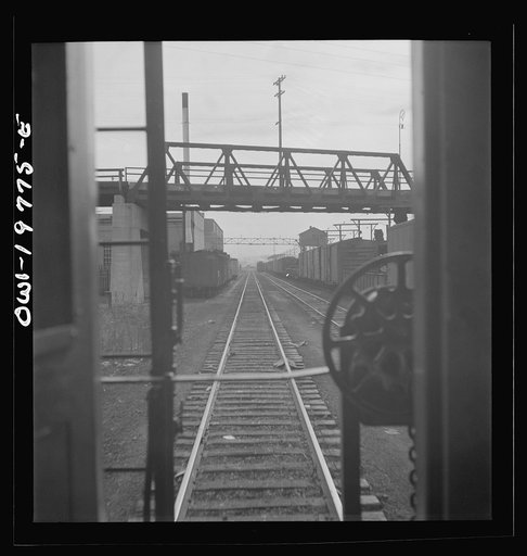 Untitled photo, possibly related to: Argentine, Kansas. Atchison, Topeka, and Santa Fe Railroad train pulling out of the railroad yard, past the giant grain elevator