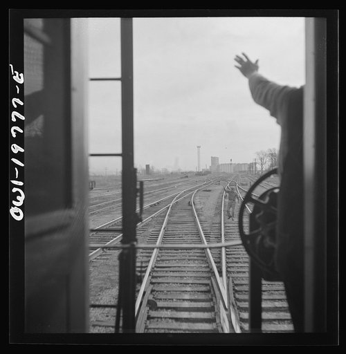 Argentine, Kansas. An Atchison, Topeka, and Santa Fe train pulling out of the railroad yard. The operator at Turner tower acknowledges receipt of the conductor's message, between Argentine and Emporia, Kansas
