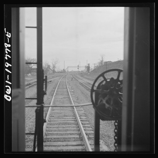 Untitled photo, possibly related to: Argentine, Kansas. Atchison, Topeka, and Santa Fe Railroad train pulling out of the railroad yard, past the giant grain elevator