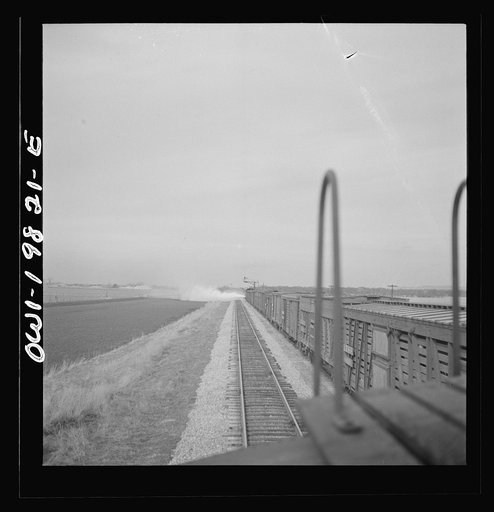 An Atchison, Topeka, and Santa Fe passenger train passing an eastbound freight train carrying stock. Steam at the head end is caused by a fireman blowing water out of the cylinders