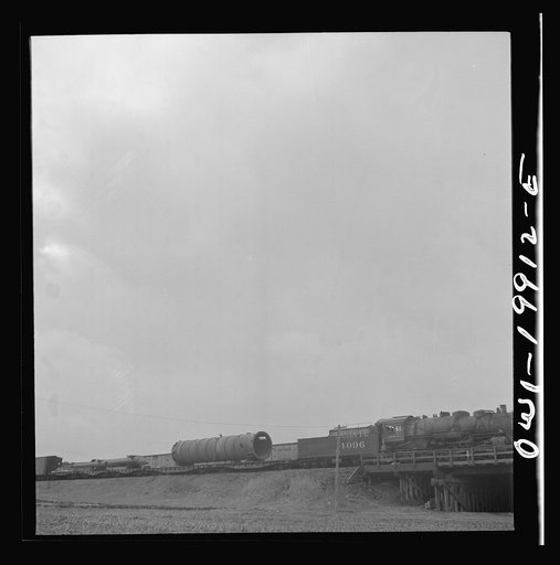 Untitled photo, possibly related to: Wellington, Kansas. Train about to leave for the West coast from the Atchison, Topeka and Santa Fe Railroad yards, carrying a huge naval gun and giant metal cylinder for the Kaiser steel mill in California