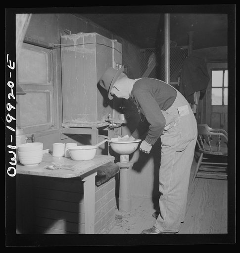 Brakeman Jack W. Torbet of Waynoka, Oklahoma washing dishes after having had lunch in the caboose on the Atchison, Topeka and Santa Fe Railroad enroute to Canadian, Texas between Waynoka, Oklahoma and Canadian, Texas
