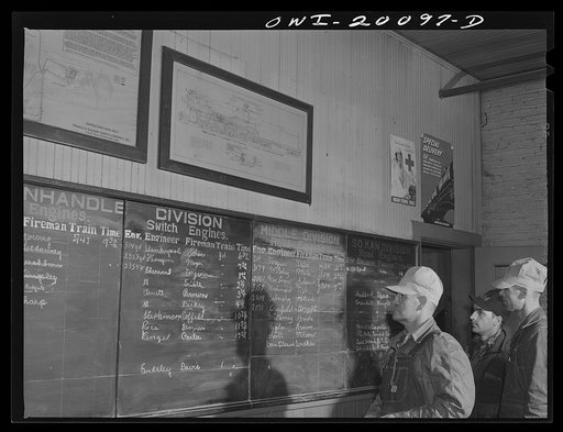 Wellington, Kansas. Atchison, Topeka and Santa Fe crew studying call board showing crew assigned to various trains. Left to right: engineer J.B. Aubuchon; brakeman W.I. Pace; and fireman Edward L. Hicks