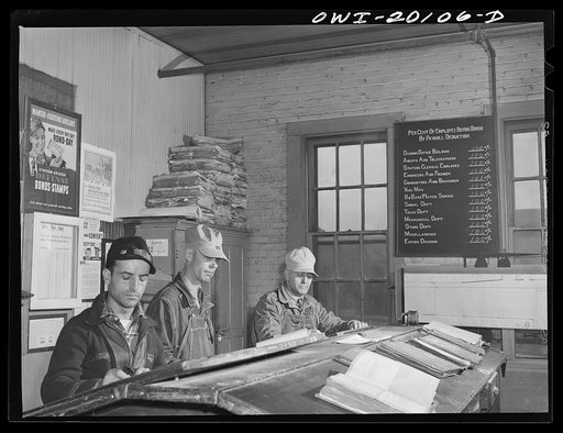 Wellington, Kansas. Atchison, Topeka and Santa Fe engine crew checking in after a day's run. Left to right: brakeman W.I. Pace; fireman Edward L. Hicks; and engineer J.B. Aubuchon. Note blackboard showing participation of railroad men in war ond campaign