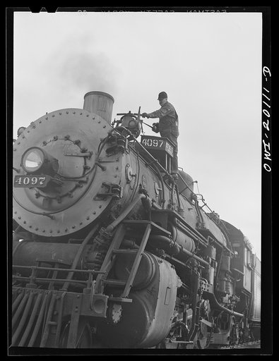 Untitled photo, possibly related to: Wellington, Kansas. Engineer B.F. Hale, of the Atchison, Topeka and Santa Fe Railroad, oiling the bell of his locomotive before pulling out of Wellington yard