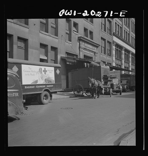 Street scene in New York City with trucks and horse drawn cart