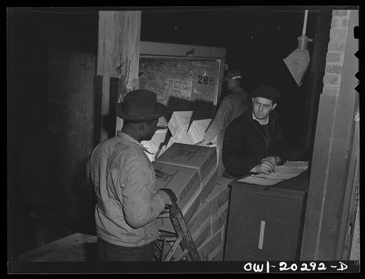 Baltimore, Maryland. A truck loader stops at the checkers desk before putting goods on a truck at Davidson truck terminal