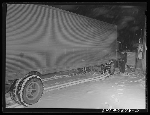Boone, North Carolina. A night attendant filling a truck with gas at three in the morning. The truck is going on to Winston-Salem