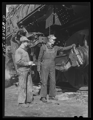 Clovis, New Mexico. Private Clarence Stephens (left) of Streator, Illinois, a member of the United States Army Railroad Battalion stationed at Clovis, with Sidney Mack, engine inspector at the Atchison, Topeka and Santa Fe Railroad shops. They are inspecting one of the 5000 Class freight engines