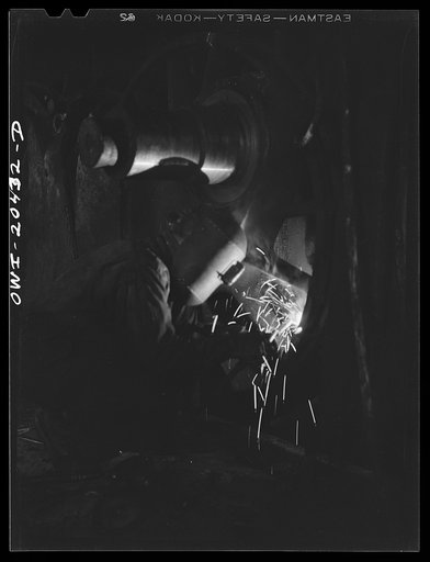 Untitled photo, possibly related to: Clovis, New Mexico. Welder at work on the driver wheel of an engine in the Atchison, Topeka and Santa Fe Railroad locomotive shop