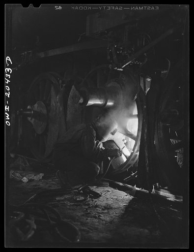 Clovis, New Mexico. Welder at work on the driver wheel of an engine in the Atchison, Topeka and Santa Fe Railroad locomotive shop