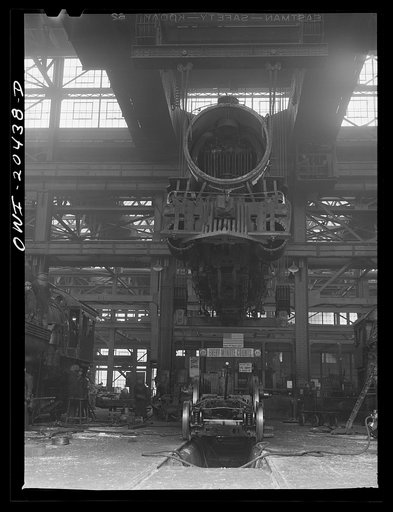 Untitled photo, possibly related to: Albuquerque, New Mexico. Wheeling an engine in the Atchison, Topeka and Santa Fe Railroad locomotive shops. The engine has been raised so high to clear the locomotive on the floor as it was carried from another part of the shop