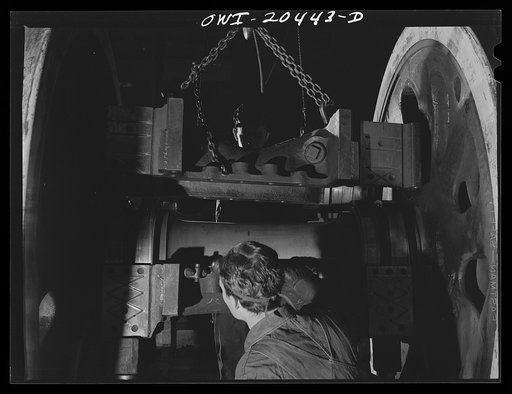Untitled photo, possibly related to: Albuquerque, New Mexico. Lowering half of a locomotive housing onto roller bearings of the driver wheel axle in the Atchison, Topeka and Santa Fe Railroad wheel shop
