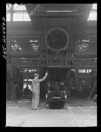 Albuquerque, New Mexico. Wheeling an engine in the Achison, Topeka and Santa Fe Railroad locomotive shops. The engine is being lowered onto its wheels on a signal from the foreman