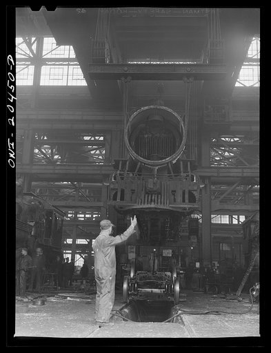 Untitled photo, possibly related to: Albuquerque, New Mexico. Wheeling an engine in the Achison, Topeka and Santa Fe Railroad locomotive shops. The engine is being lowered onto its wheels on a signal from the foreman