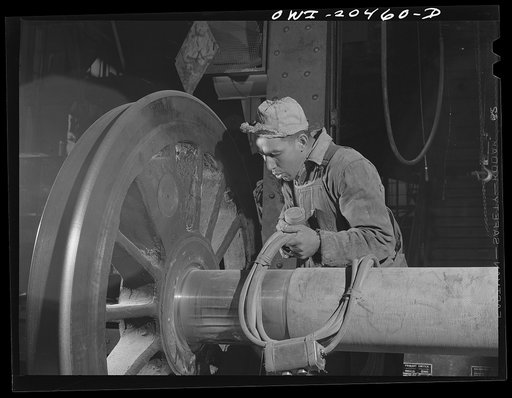 Albuquerque, New Mexico. Magnaflux inspector A.J. Fry at work on an engine wheel axle in the Atchison, Topeka and Santa Fe Railroad shop. The cable in his hand magnetizes the axle as he spreads steel dust over an area. He then cuts the current off and carefully blows the dust away. The steel particl