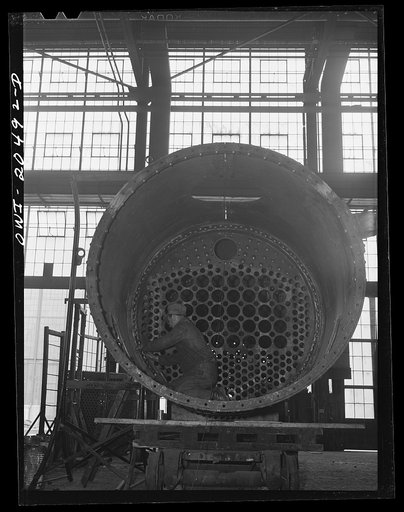 Untitled photo, possibly related to: Albuquerque, New Mexico. Workmen making inspection of newly-driven rivets in a flue sheet and boiler seam in the Atchison, Topeka and Santa Fe Railroad locomotive shops