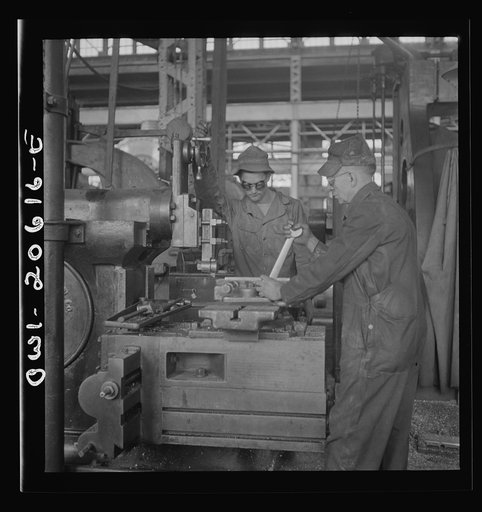 Untitled photo, possibly related to: Clovis, New Mexico. Private Frank Donath of Sedalia, Missouri, learning to use a shaper under the direction of A.R. Rose, machinist at the Atchison, Topeka and Santa Fe Railroad locomotive shops. Private Donath is a member of the United States Army railroad batta
