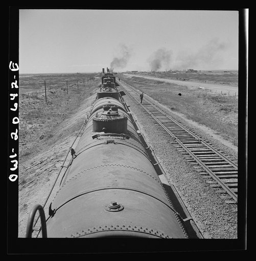 Untitled photo, possibly related to: Tolar, New Mexico. Atchison, Topeka, and Santa Fe Railroad train between Clovis and Vaughn, New Mexico stopping for water. A brakeman walking the length of the train for inspection