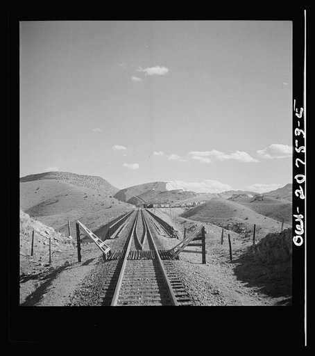 Coming out of the mountains on the Atchison, Topeka and Santa Fe Railroad between Vaughn and Belen, New Mexico into the Rio Grande River Valley. In the distance is a quarry on the mountainside where the railroad gets its rock for ballast