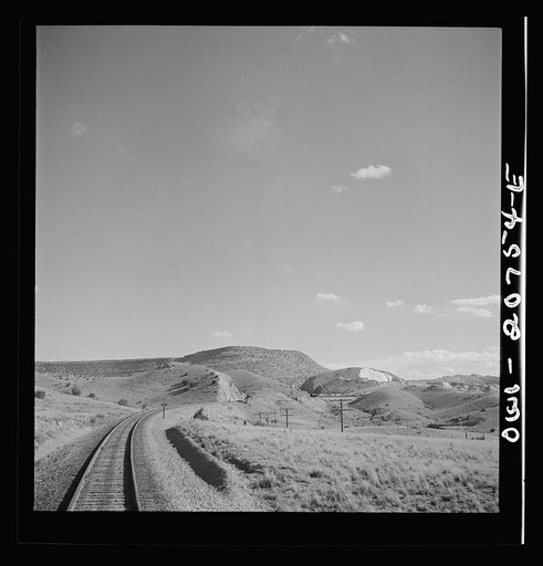 Coming out of the mountains on the Atchison, Topeka and Santa Fe Railroad between Vaughn and Belen, New Mexico into the Rio Grande River Valley. In the distance is a quarry on the mountainside where the railroad gets its rock for ballast