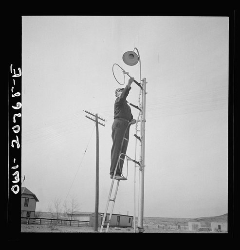 Untitled photo, possibly related to: Isleta, New Mexico. Mr. Young standing on hoops with messages to be picked up by passing train on the Atchison, Topeka and Santa Fe Railroad