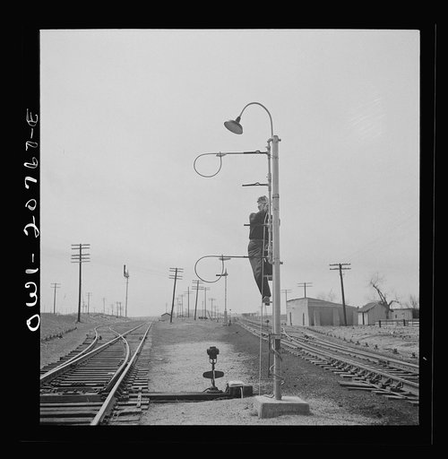 Isleta, New Mexico. Mr. Young standing on hoops with messages to be picked up by passing train on the Atchison, Topeka and Santa Fe Railroad