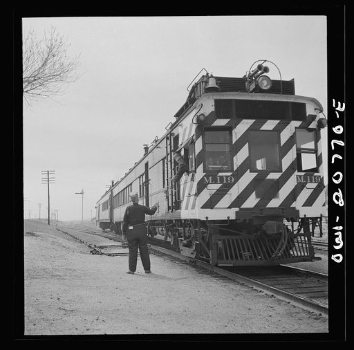 Isleta, New Mexico. Engineer of a passenger train on the Atchison, Topeka and Santa Fe Railroad picking up a message passed to him by the agent, by hand. This diesel train called the "Doodle Bug" makes all local stops