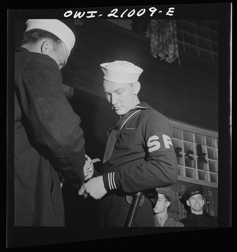 Washington, D.C. Member of the Shore Patrol who helps get servicemen lined up and in order while waiting for special buses to leave the Greyhound bus terminal on Sunday evenings